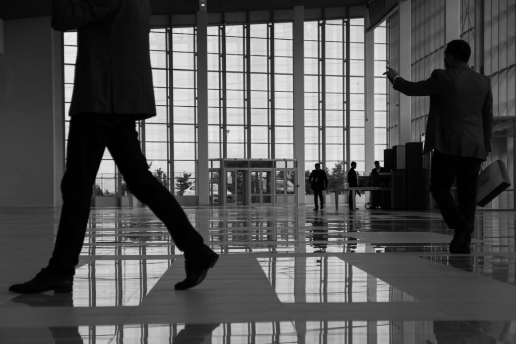 Business professionals walk through a modern, glass-paneled indoor space.