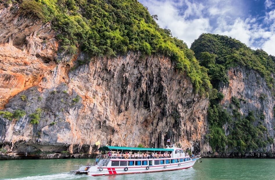 A boat cruise offers breathtaking views of lush cliffs under a bright blue sky.